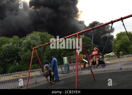 L'AUTORISATION PARENTALE A PERMIS aux personnes se trouvant dans un parc alors que de la fumée s'est enflamée dans un domaine industriel de Birmingham. Les équipes de 10 moteurs d'incendie s'attaquent à l'incendie. Banque D'Images