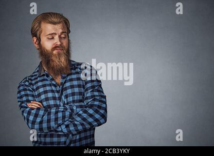 Suspect sceptique homme regardant le côté de copyspace. Petit garçon avec barbe en bleu écossais à carreaux isolés sur gris gris studio Backgro Banque D'Images