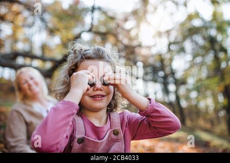 Petite fille avec grand-mère sur une promenade dans la forêt d'automne, s'amuser. Banque D'Images