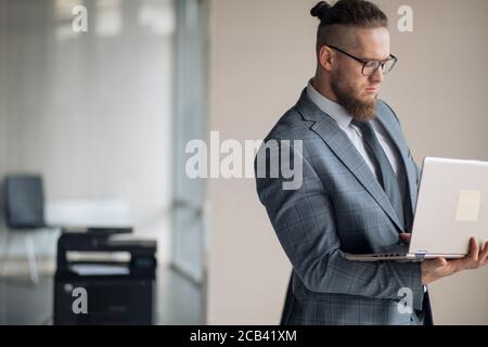 jeune homme d'affaires élégant avec ordinateur portable, debout dans une chambre moderne. vue rapprochée sur le côté. espace pour copier Banque D'Images