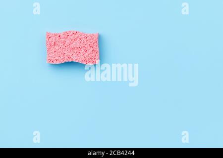 Disposition créative avec éponge pour laver la vaisselle sur fond bleu. Banque D'Images