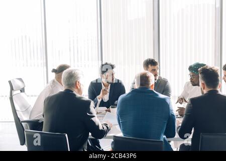 Équipe multiethnique assise dans la salle de conférence pendant une réunion, discutant et planifiant un investissement à long terme Banque D'Images