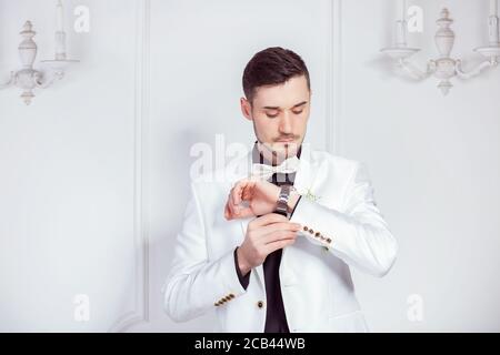 Magnifique tenue moderne en costume élégant de luxe avec montre-bracelet réglable boutons de manchette et debout sur fond blanc Banque D'Images