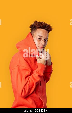 Style libre. Mulatto gars en sweat à capuche isolé sur jaune posant à la caméra confiante vue latérale Banque D'Images