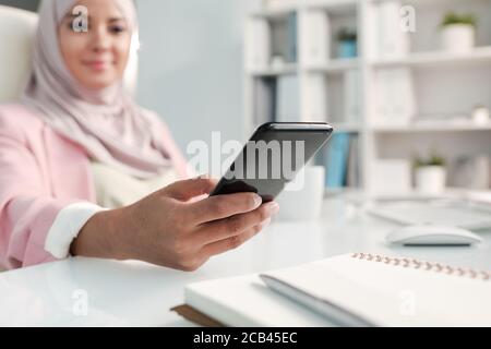 Gros plan sur une femme musulmane utilisant un smslartphone tout en répondant à un sms bureau Banque D'Images