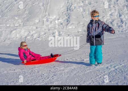 Frère tirant sa sœur enfants luge neige de traîneau. Petite fille et petit garçon en traîneau. Enfants traîneaux. Les enfants jouent à l'extérieur dans la neige. Traîneau pour enfants. Banque D'Images