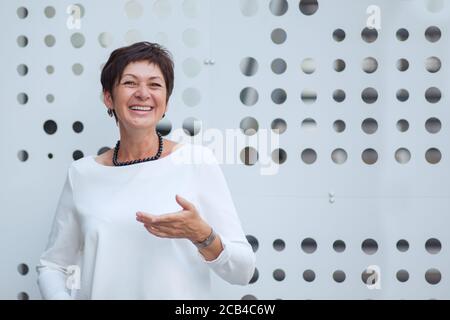 Joyeuse femme moderne d'âge moyen qui riait avec éclat à la caméra dans la rue mur Banque D'Images