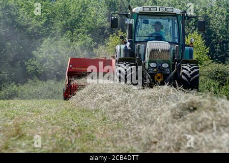 Trossingen, Allemagne, 25 juin 2020. Tracteur Fendt 313 moderne dans les champs, pressage du foin dans les balles avec une presse à balles Welger de quarante ans. Banque D'Images