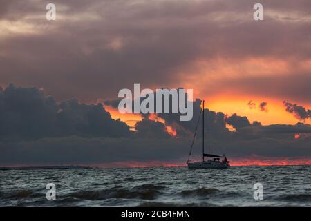 Voilier pendant un coucher de soleil sur la mer tropicale, ciel dramatique sur l'arrière-plan. Concept croisière et yacht Banque D'Images