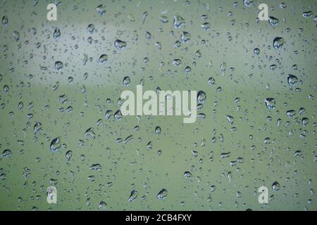 Gros plan de verre avec gouttes de pluie sur fond naturel, gouttes d'eau sur verre de voiture, mise au point sélective Banque D'Images
