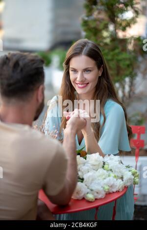 Couple assis à la table, regardant l'un l'autre, tenant les mains Banque D'Images