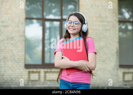 Les filles méritent le monde. Obtenez des connaissances de l'ebook. Éducation scolaire moderne. Retour à l'école. Livre de travail de l'adolescent heureux. Dossiers de garde d'enfant souriant. Bonheur d'enfance. Fille dans l'oreillette écouter de la musique. Banque D'Images