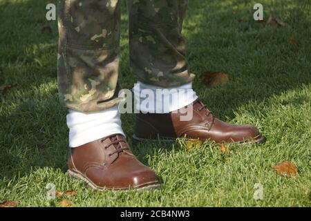 Gros plan des pieds mâles portant des chaussures en cuir marron et caleçons de camouflage Banque D'Images