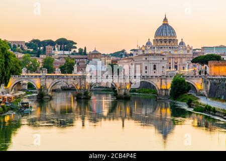 Vue sur la basilique Saint-Pierre et la Cité du Vatican au coucher du soleil le long du Tibre à Rome, en Italie Banque D'Images