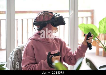 Une jeune fille porte des lunettes vr casque explorant la réalité virtuelle assis dans une chaise. Banque D'Images