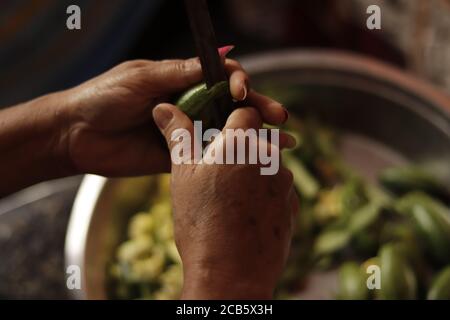 Mère indienne coupant des légumes verts avec un couteau à tranchant fermé haut Banque D'Images