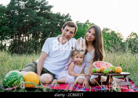 belle famille, maman, papa et fille assis sur un pique-nique avec la pastèque. Banque D'Images