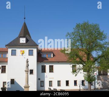 République tchèque, Prague, Dolni Pocernice, 21 avril 2018 : ancien village Hôtel de ville avec horloge et staue en pierre, arbre vert et fond bleu ciel Banque D'Images