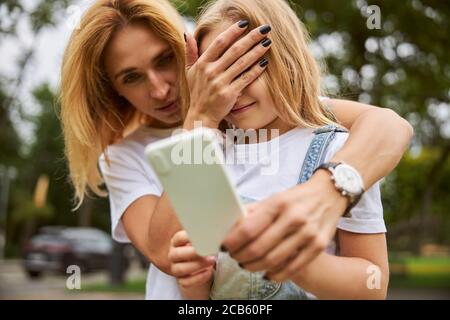 Belle femme blonde tournant les yeux aveugles avec la main à sa fille Banque D'Images