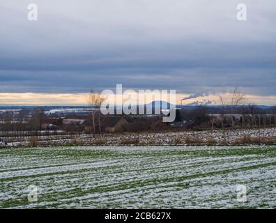 Paysage rural d'hiver avec des champs couverts de neige verte au coucher du soleil. Vue sur la montagne RIP colline avec cheminée, populaire lieu de pèlerinage, central Banque D'Images