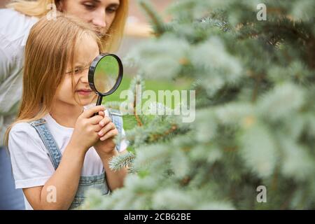 Jeune fille tenant la lentille dans les mains tout en passant du temps avec professeur dans le parc Banque D'Images