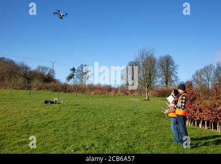 Deux photographes professionnels volant un drone avec un appareil photo Terrain privé dans les Cotswolds Banque D'Images