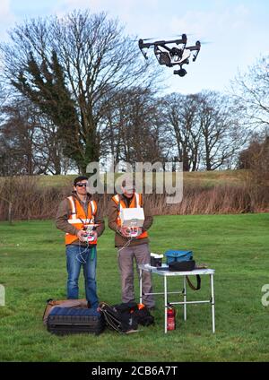 Deux photographes aiment voler un drone avec un appareil photo dedans Un grand jardin de campagne dans les Cotswolds Banque D'Images