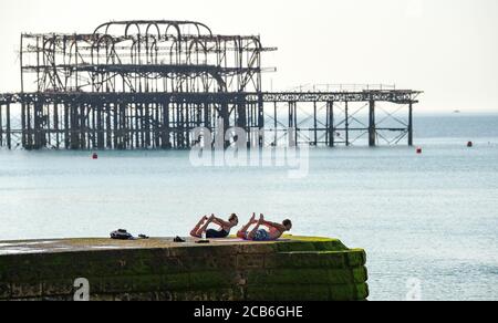 Brighton Royaume-Uni 11 août 2020 - ce couple profitez du yoga par temps chaud sur la plage de Brighton un autre jour ensoleillé que les températures devraient atteindre à nouveau bien au-dessus de 30 degrés dans certaines parties du Sud-est tandis que d'autres parties du pays sont touchées par les tempêtes de tonnerre : Credit Simon Dack / Alamy Live News Banque D'Images
