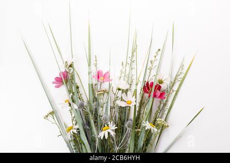 Bouquet festif de roses et pourpres, fleurs sauvages blanches, cosmétiques, herbes sur fond blanc Banque D'Images
