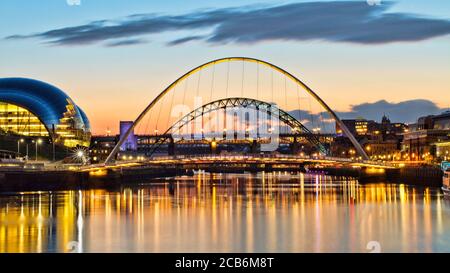 Vue sur la rivière Tyne vers les ponts emblématiques de Tyne, du millénaire et de haut niveau. Capturé au coucher du soleil avec des reflets dans l'eau. Banque D'Images