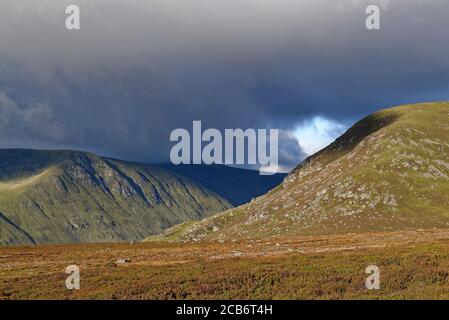 Des nuages sombres surpassent Glen Clova dans les Glens Angus, le matin ensoleillé de septembre, depuis le sentier jusqu'au Loch Brandy. Banque D'Images