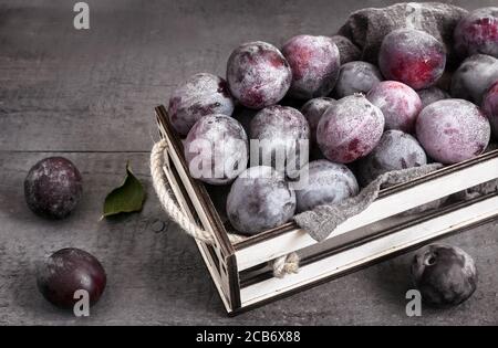 Grands prunes mûres dans un récipient sur la table Banque D'Images