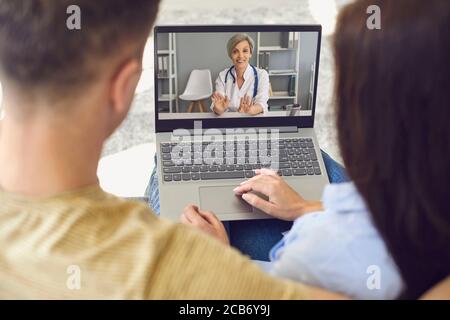 Consultation en ligne avec des médecins. Un couple a un appel vidéo avec des médecins utilisant un ordinateur portable dans la chambre. Banque D'Images