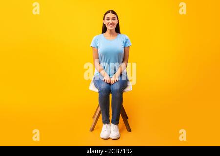 Photo studio d'une jeune femme assise sur la chaise Banque D'Images
