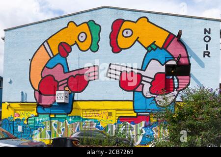 Angleterre London Stratford Park Hackney Wick graffiti Noir deux géants personnages jouant guitares mur de brique entrepôt hangar Banque D'Images