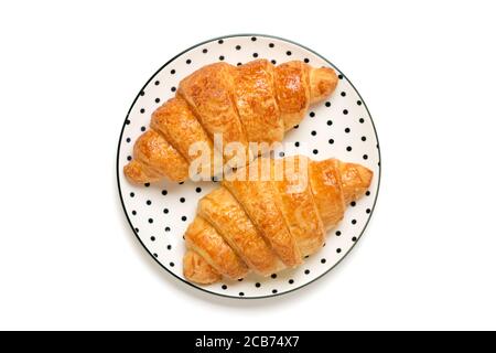 Croissants frais français au chocolat sur une assiette blanche tendance avec Pois noirs isolés sur fond blanc petit-déjeuner continental le matin Haut Vue à plat Banque D'Images