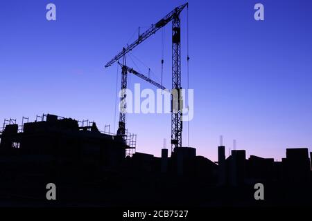Chantier de construction avec grues à la tombée de la nuit Banque D'Images