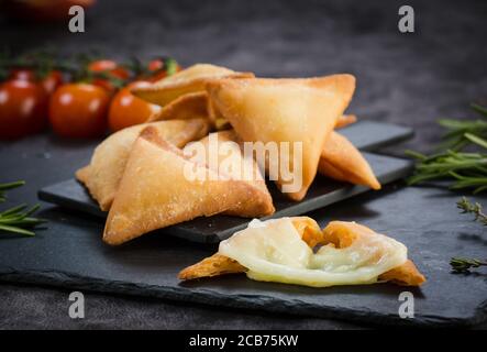 Fromage maison fraîchement cuit, pâtisseries savoureuses dans un cadre rustique. Samosa au fromage. Banque D'Images