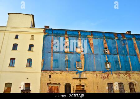 La façade d'un vieux bâtiment ruineux est tachetée des rideaux bleus pour protéger les piétons Banque D'Images