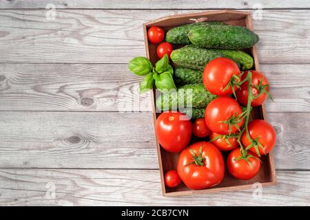 Vue de dessus d'un récipient en bois plein de tomates mûres, rouges et juteuses récoltées Banque D'Images