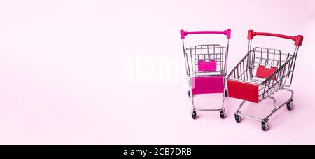 Vider les mini-chariots sur fond rose. Shopping, achats, supermarché, vente, concept de centre commercial Banque D'Images