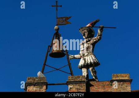 Dire l'heure à toute la ville. Une figure automatisée en bois, vêtue de costume de clown métallique, frappe les heures au sommet d'une tour, la Torre di Pulcinella (Tour de «Jr Punch»), sur la Piazza Michelozzo, Montepulciano, Toscane, Italie. Pulcinella était un personnage qui est apparu dans la commedia italienne dell’arte en 1600s. Banque D'Images