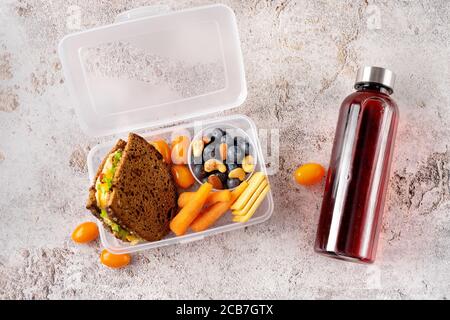 Vue de dessus de vegan et saine école déjeuner et bouteille avec du jus sur fond en béton gris Banque D'Images