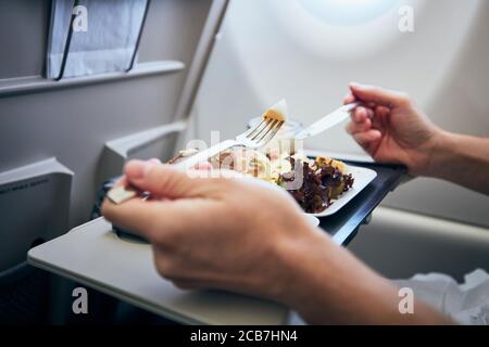 Homme mangeant un repas de compagnie aérienne servi sur les tables de sièges pendant le vol. Banque D'Images