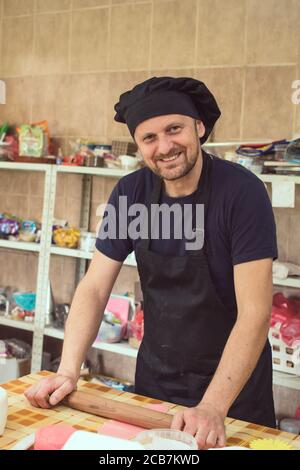 Chef pâtissier à l'aide d'une broche roulante sur un morceau de pâte. Faire la décoration de gâteau Banque D'Images