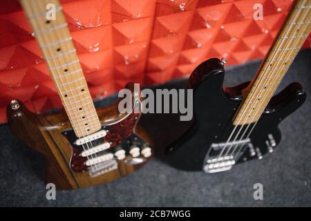 Deux guitares rognées ont été fixées sur un mur rouge Banque D'Images