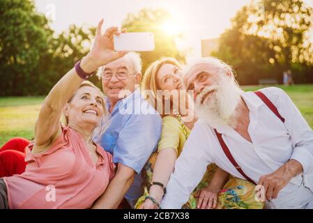 Groupe d'aînés faisant un pique-nique au parc et s'amusant. Banque D'Images