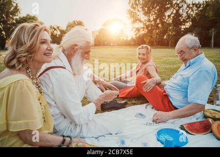 Groupe d'aînés faisant un pique-nique au parc et s'amusant. Banque D'Images