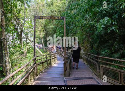 Passerelle dans le circuit supérieur du parc national d'Iguazu. Touristes en chemin à travers la forêt. Affiche suspendue d'entrée. Banque D'Images