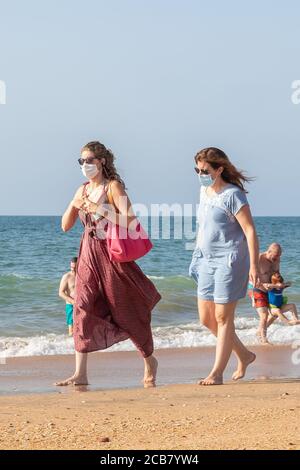 Punta Umbria, Huelva, Espagne - 7 août 2020 : deux femmes marchant sur la plage portant des masques protecteurs ou médicaux. Nouvelle normale en Espagne avec social Banque D'Images